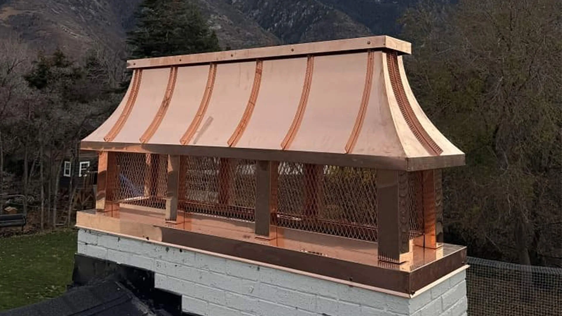 Copper concave-roof chimney cap installed on a home