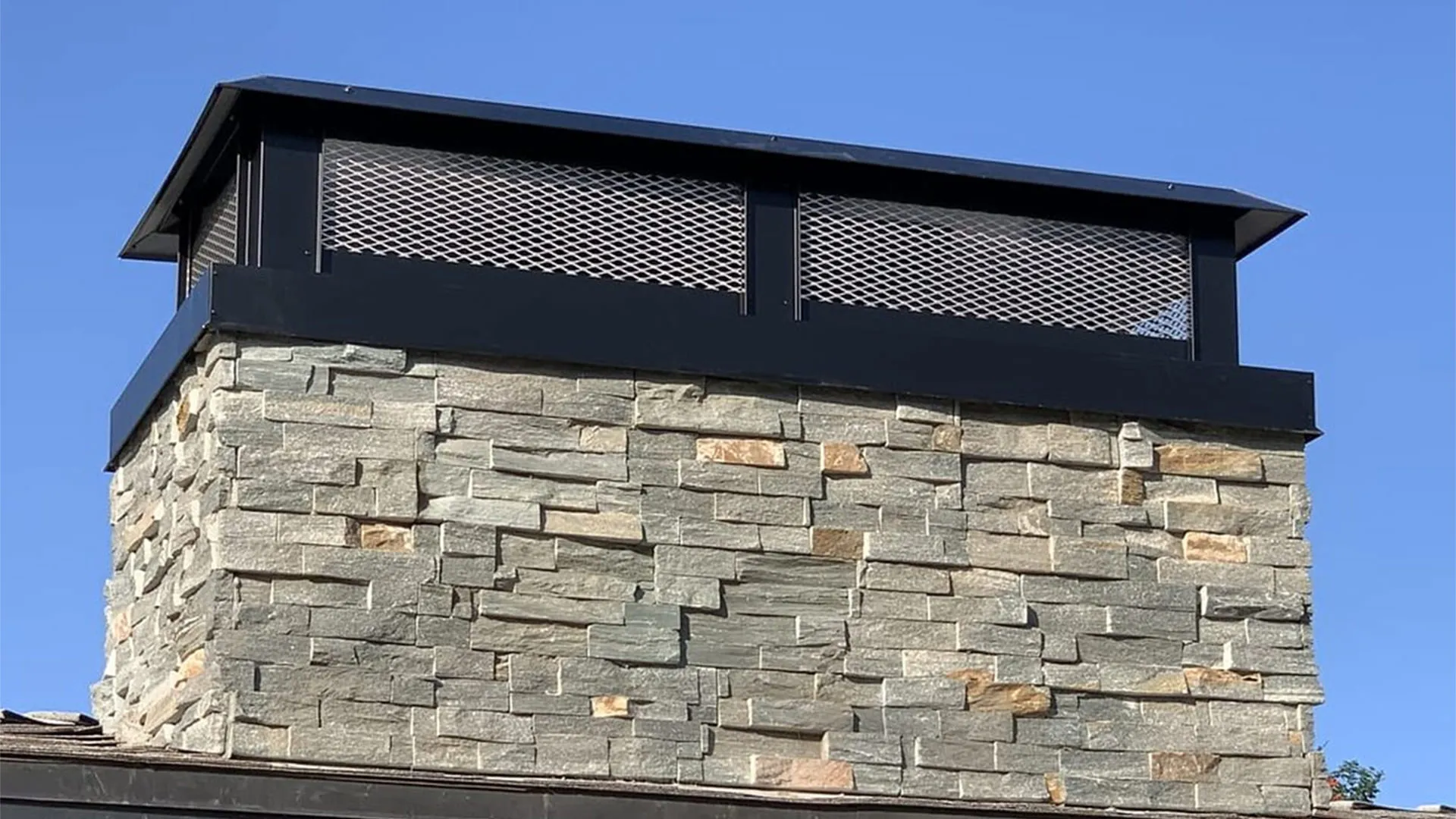 Black aluminum flat-roof chimney cap installed on a home